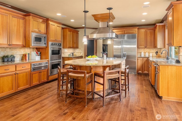 kitchen featuring built in appliances, a sink, a warming drawer, decorative backsplash, and brown cabinetry