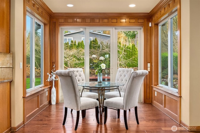 dining space with wood finished floors, ornamental molding, a decorative wall, recessed lighting, and wooden walls