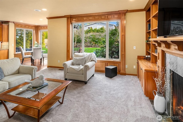 living area with crown molding, a high end fireplace, light colored carpet, baseboards, and recessed lighting