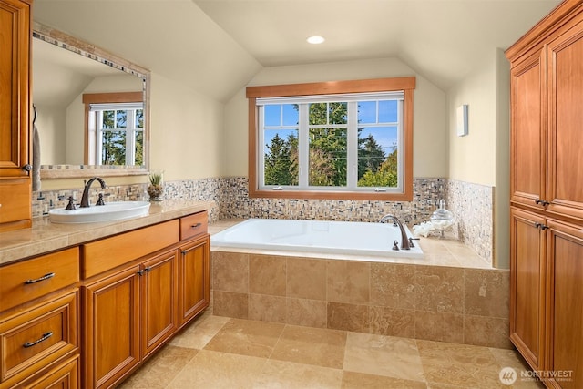 bathroom with plenty of natural light, a garden tub, vaulted ceiling, vanity, and recessed lighting