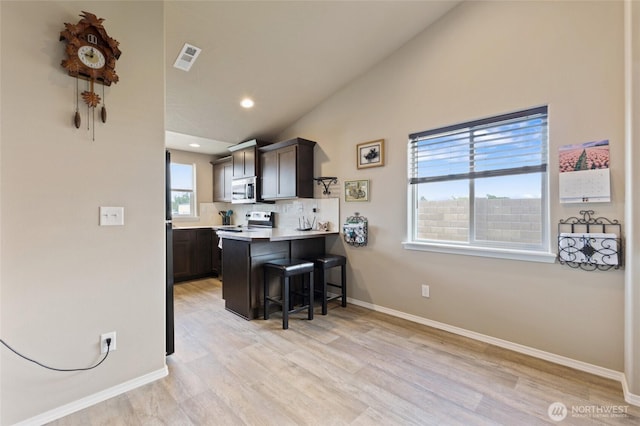 1003 NE Aspen Rd, Moses Lake, WA 98837 - kitchen with stainless steel appliances, a kitchen bar, baseboards, light wood-style floors, and a peninsula