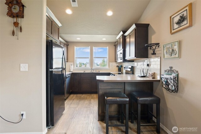 1003 NE Aspen Rd, Moses Lake, WA 98837 - kitchen featuring stainless steel appliances, a peninsula, a sink, light wood finished floors, and a kitchen breakfast bar
