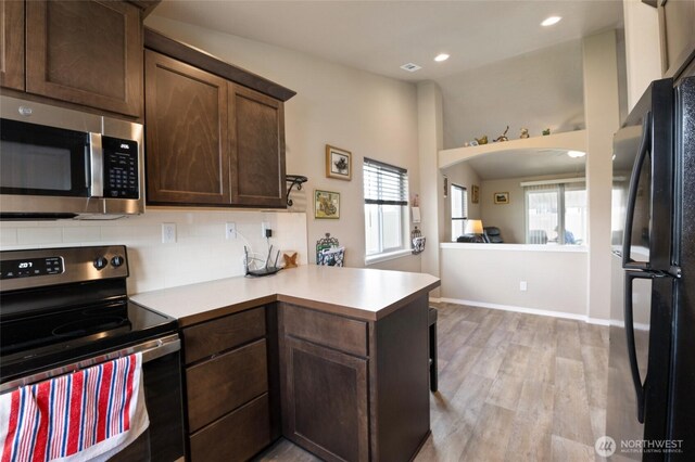 1003 NE Aspen Rd, Moses Lake, WA 98837 - kitchen featuring black appliances, a peninsula, light countertops, light wood-style floors, and dark brown cabinets