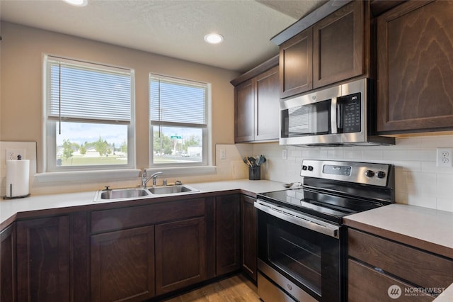 1003 NE Aspen Rd, Moses Lake, WA 98837 - kitchen with appliances with stainless steel finishes, a sink, tasteful backsplash, dark brown cabinets, and light countertops