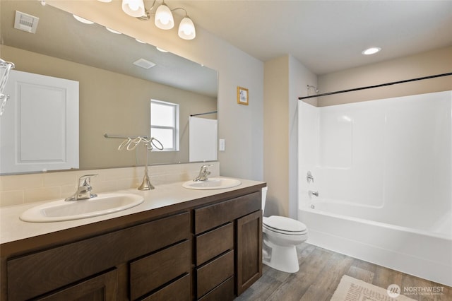 1003 NE Aspen Rd, Moses Lake, WA 98837 - full bathroom featuring toilet, wood finished floors, double vanity, and tub / shower combination
