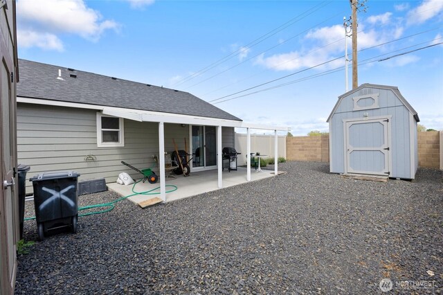 1003 NE Aspen Rd, Moses Lake, WA 98837 - rear view of house featuring a shingled roof, a storage shed, a patio, a fenced backyard, and an outdoor structure