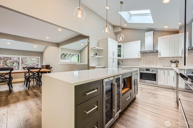 14323 SE 49th St, Bellevue, WA 98006 - kitchen featuring stainless steel appliances, wall chimney exhaust hood, white cabinetry, lofted ceiling, and wine cooler