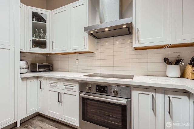14323 SE 49th St, Bellevue, WA 98006 - kitchen with stainless steel oven, wall chimney range hood, tasteful backsplash, and white cabinets