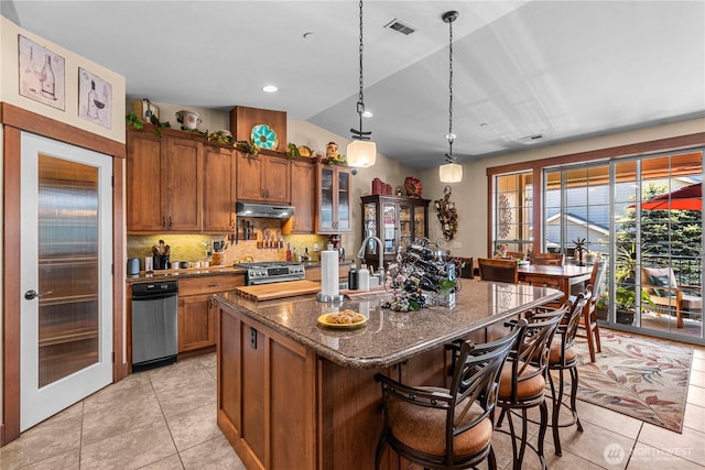 1051 N Baker Ave Unit B204, East Wenatchee, WA 98802 - kitchen with brown cabinetry, light tile patterned flooring, vaulted ceiling, dark stone counters, and a breakfast bar area