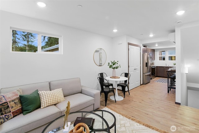 living area featuring light wood-type flooring, plenty of natural light, recessed lighting, and a wall mounted AC