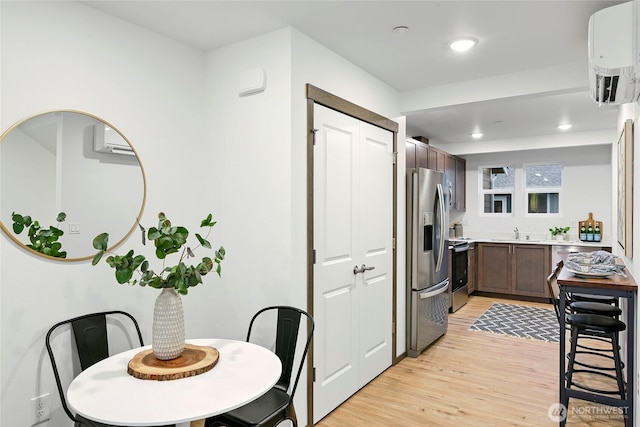 kitchen featuring stainless steel fridge with ice dispenser, electric range, a sink, light countertops, and light wood finished floors