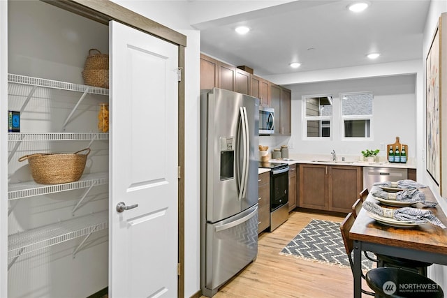 kitchen with stainless steel appliances, light wood-type flooring, a sink, light countertops, and recessed lighting