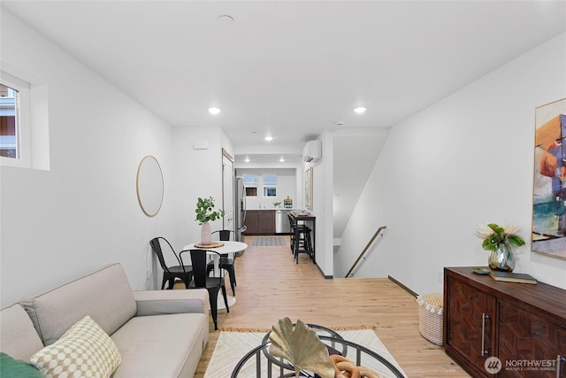living area with light wood-type flooring, a wall mounted AC, and recessed lighting
