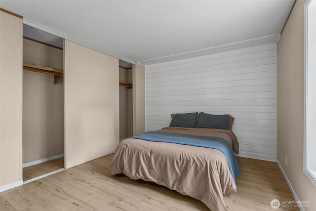 260 E Tahuya Dr, Shelton, WA 98584 - bedroom featuring wood finished floors, wood walls, two closets, and baseboards