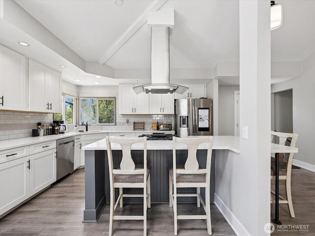 7315 294th St NE, Arlington, WA 98223 - kitchen with stainless steel appliances, island range hood, a kitchen breakfast bar, decorative backsplash, and white cabinetry