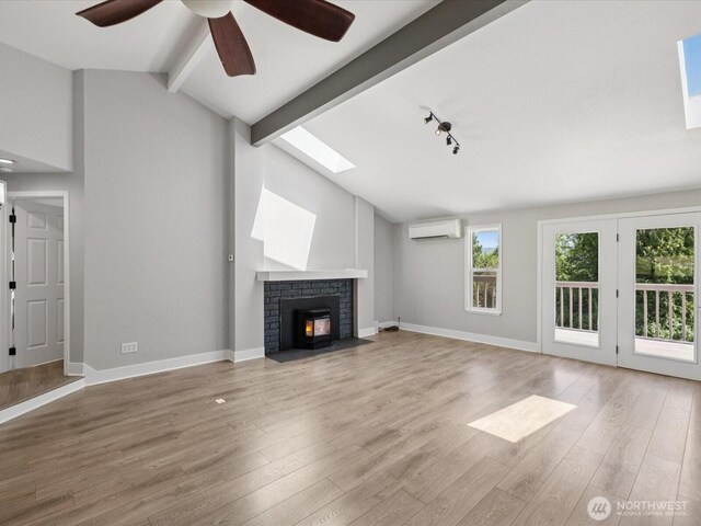 7315 294th St NE, Arlington, WA 98223 - unfurnished living room featuring a wall unit AC, a brick fireplace, a skylight, wood finished floors, and ceiling fan