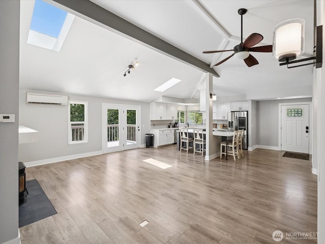 7315 294th St NE, Arlington, WA 98223 - living room featuring a skylight, a wall mounted air conditioner, a ceiling fan, a wood stove, and light wood-style floors