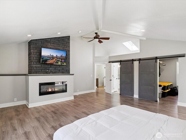 7315 294th St NE, Arlington, WA 98223 - bedroom featuring a barn door, beam ceiling, wood finished floors, a fireplace, and a walk in closet