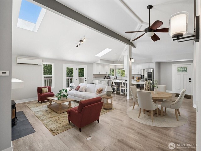 7315 294th St NE, Arlington, WA 98223 - living room featuring an AC wall unit, a skylight, a wood stove, a ceiling fan, and light wood-style floors