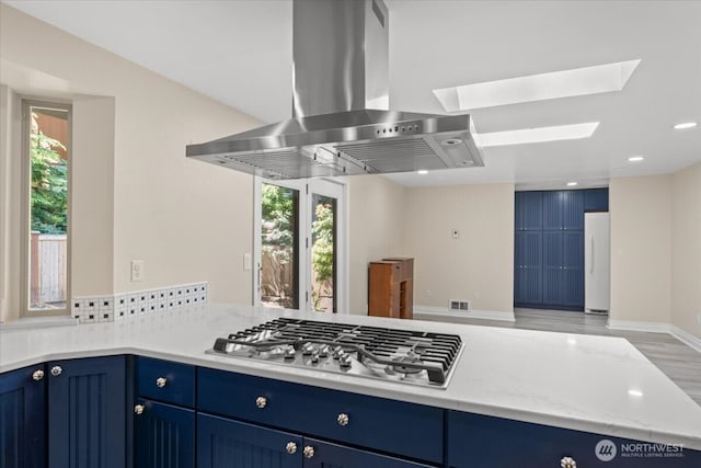 447 E Pointes Dr E, Shelton, WA 98584 - kitchen featuring island exhaust hood, freestanding refrigerator, blue cabinetry, stainless steel gas stovetop, and a skylight