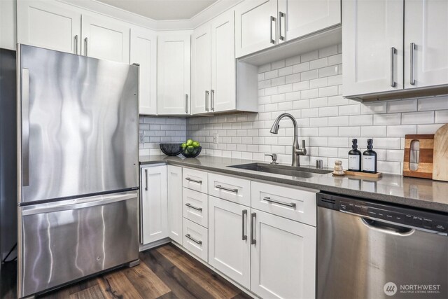 769 Hayes St Unit 504, Seattle, WA 98109 - kitchen with appliances with stainless steel finishes, a sink, white cabinets, decorative backsplash, and dark stone countertops