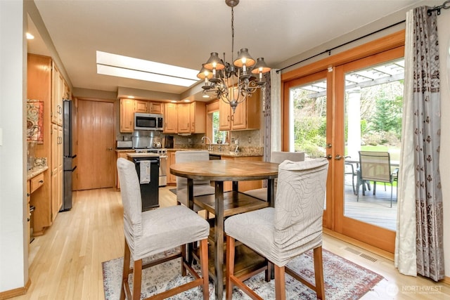 2634 59th Ave NW, Olympia, WA 98502 - dining space featuring light wood finished floors, a chandelier, french doors, and a skylight