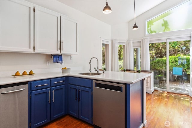 kitchen with stainless steel dishwasher, blue cabinets, a sink, white cabinetry, and a peninsula