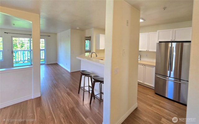 18501 SE Newport Way Unit H335, Issaquah, WA 98027 - kitchen with freestanding refrigerator, baseboards, wood finished floors, and white cabinetry