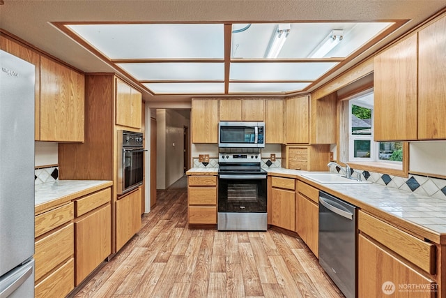 58 Pacific Pl, Longview, WA 98632 - kitchen featuring appliances with stainless steel finishes, a sink, light wood-style flooring, and tile countertops