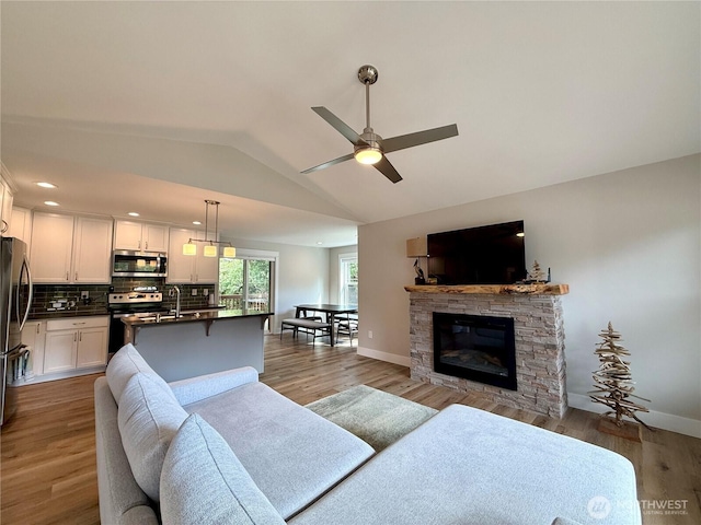 335 N Wynoochee Dr SW, Ocean Shores, WA 98569 - living area with lofted ceiling, ceiling fan, light wood finished floors, a fireplace, and baseboards