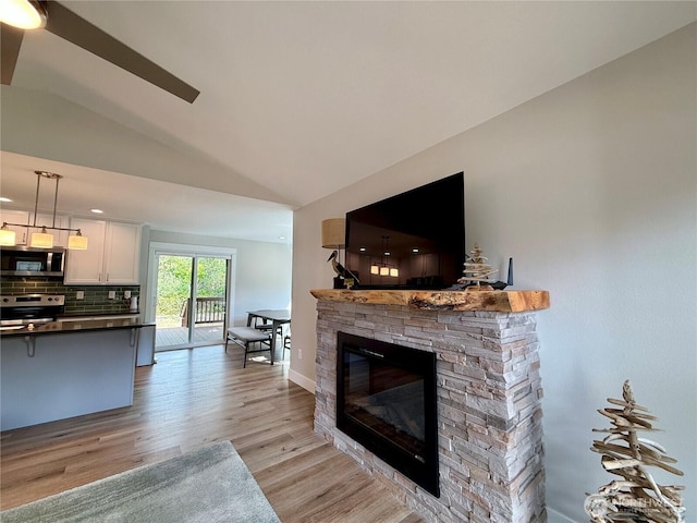 335 N Wynoochee Dr SW, Ocean Shores, WA 98569 - living area featuring light wood-type flooring, a stone fireplace, lofted ceiling, and baseboards