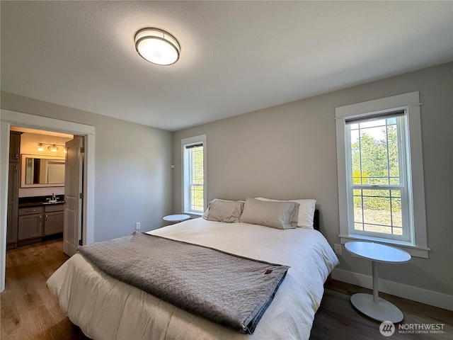 335 N Wynoochee Dr SW, Ocean Shores, WA 98569 - bedroom with wood finished floors, multiple windows, baseboards, and a sink