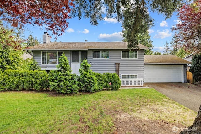 view of front of home with a chimney, a front yard, and a garage