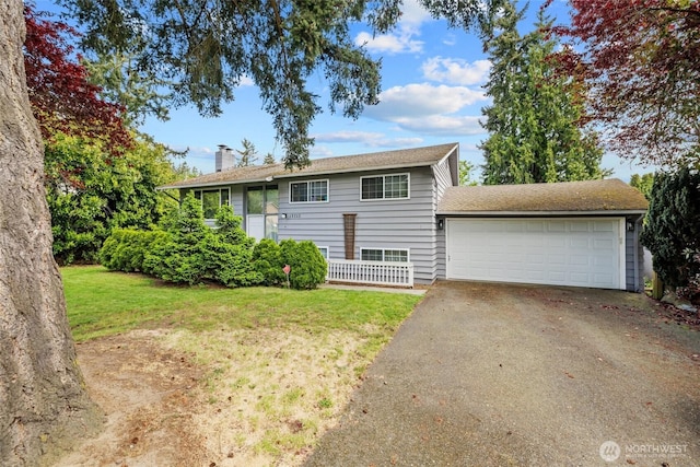 raised ranch featuring a chimney, asphalt driveway, a front lawn, and a garage