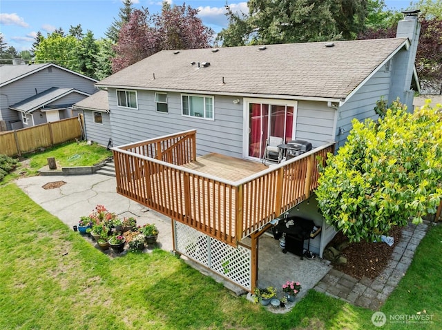 back of house with a patio area, a wooden deck, roof with shingles, and a chimney