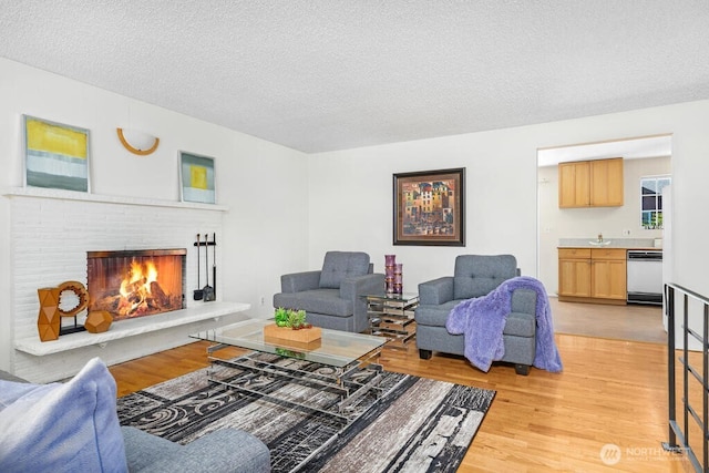 living area featuring light wood-type flooring, a textured ceiling, and a fireplace