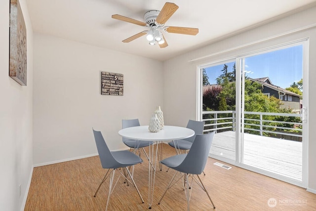 dining space featuring wood finished floors, baseboards, and a ceiling fan