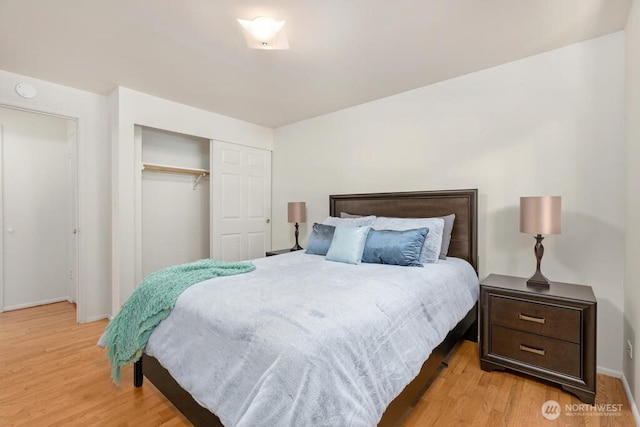bedroom with light wood finished floors, a closet, and baseboards