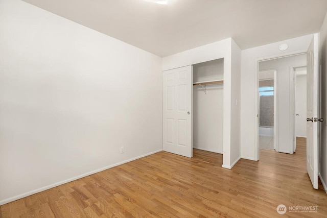 unfurnished bedroom with baseboards, light wood-type flooring, and a closet