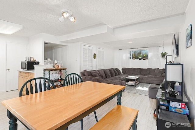 dining area with a textured ceiling and light wood-style flooring