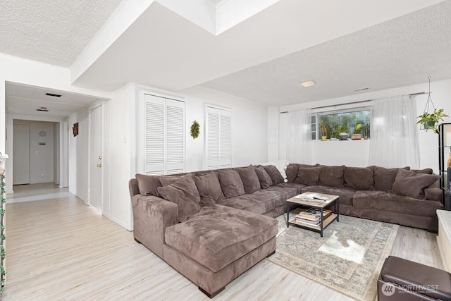 living room featuring wood finished floors, a textured ceiling, and baseboards