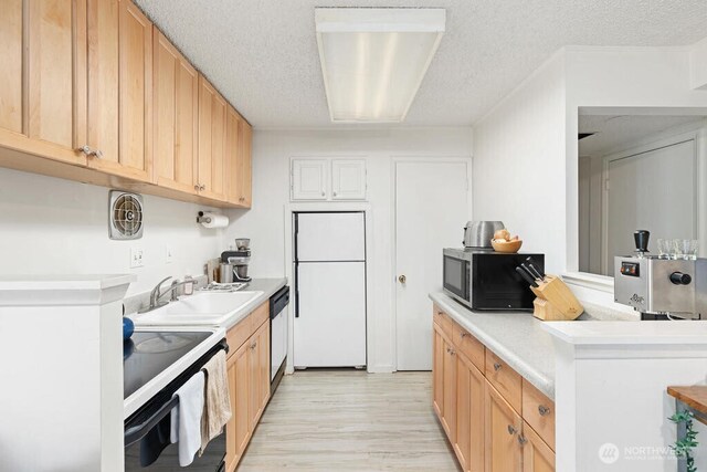 kitchen featuring freestanding refrigerator, stainless steel microwave, electric range oven, a sink, and light countertops