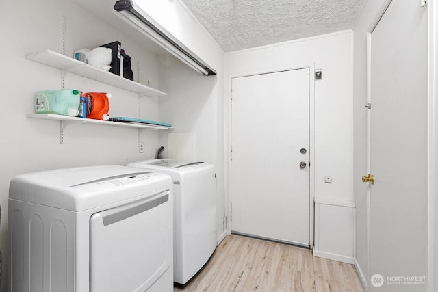 washroom with separate washer and dryer, light wood-style flooring, and a textured ceiling