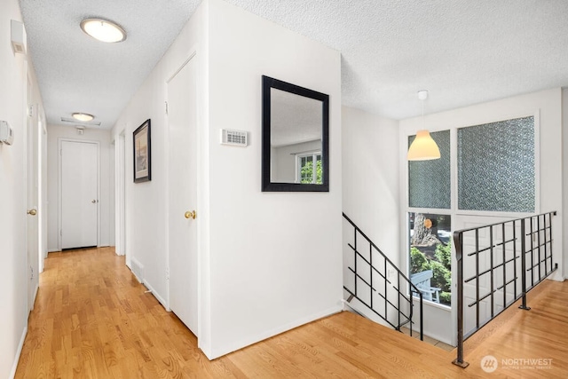 corridor with a textured ceiling, wood finished floors, and baseboards