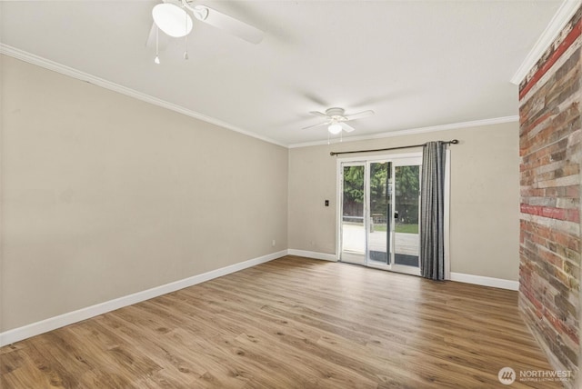 spare room featuring a ceiling fan, baseboards, crown molding, wood finished floors, and brick wall