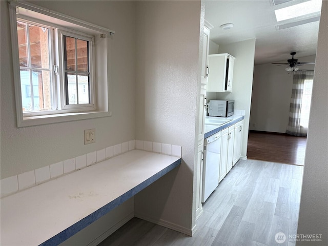 1710 263rd St, Ocean Park, WA 98640 - kitchen featuring white dishwasher, white cabinets, light wood-style flooring, a skylight, and baseboards