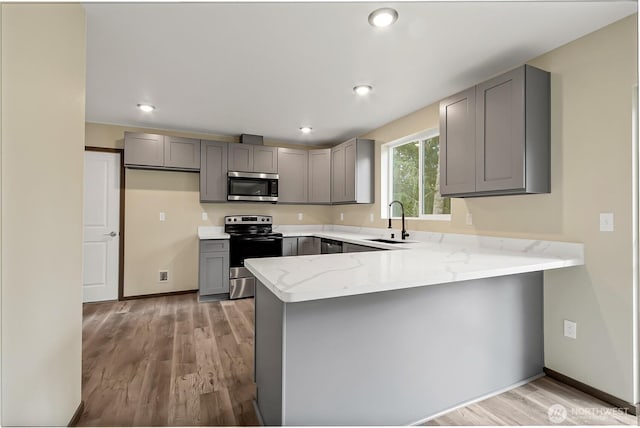 20116 58th Ave E, Spanaway, WA 98387 - kitchen with stainless steel appliances, gray cabinetry, a sink, a peninsula, and light stone counters