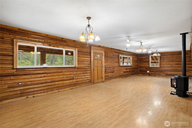 4193 Sparks Rd, Easton, WA 98925 - unfurnished living room featuring a wood stove, wood finished floors, ceiling fan, rustic walls, and a chandelier