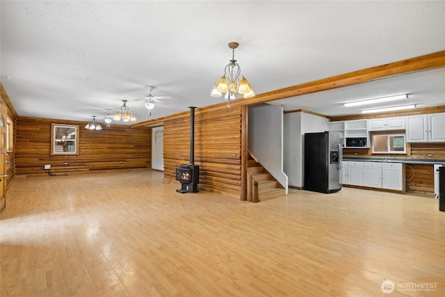 4193 Sparks Rd, Easton, WA 98925 - unfurnished living room with a wood stove, light wood finished floors, stairway, a chandelier, and a ceiling fan