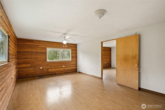 4193 Sparks Rd, Easton, WA 98925 - empty room featuring wood finished floors, log walls, a ceiling fan, and baseboards